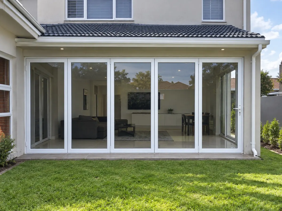 White aluminium folding glass doors opening onto a garden